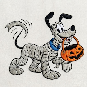 Puede incluir: Un parche bordado que muestra un perro de dibujos animados envuelto en vendas de momia grises con un collar azul. El perro tiene orejas y cola negras y sostiene un cubo de calabaza naranja en la boca sobre un fondo blanco liso.