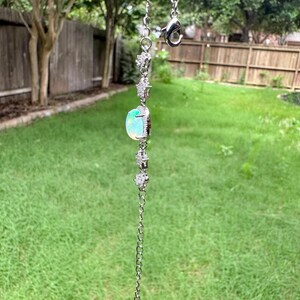 May include: A silver-toned chain bracelet featuring a central oval-shaped iridescent opal stone flanked by two small star-shaped charms encrusted with clear crystals. The bracelet includes a lobster claw clasp and a delicate link chain design.