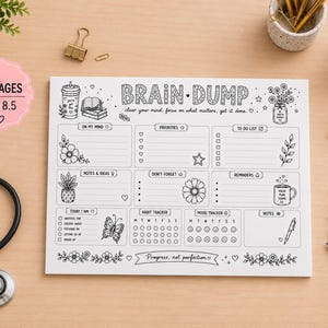May include: A white paper planner pad with black ink text and illustrations titled Brain Dump. It features sections for priorities, to-do lists, habit and mood trackers, and notes. The pad is labeled 50 pages and 11 x 8.5 inches.