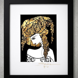 May include: A framed art print featuring a stylized illustration of a figure with voluminous gold hair against a solid black background. The figure has white skin, dark eyes, and red lips. A gold signature is visible at the bottom of the white mat.