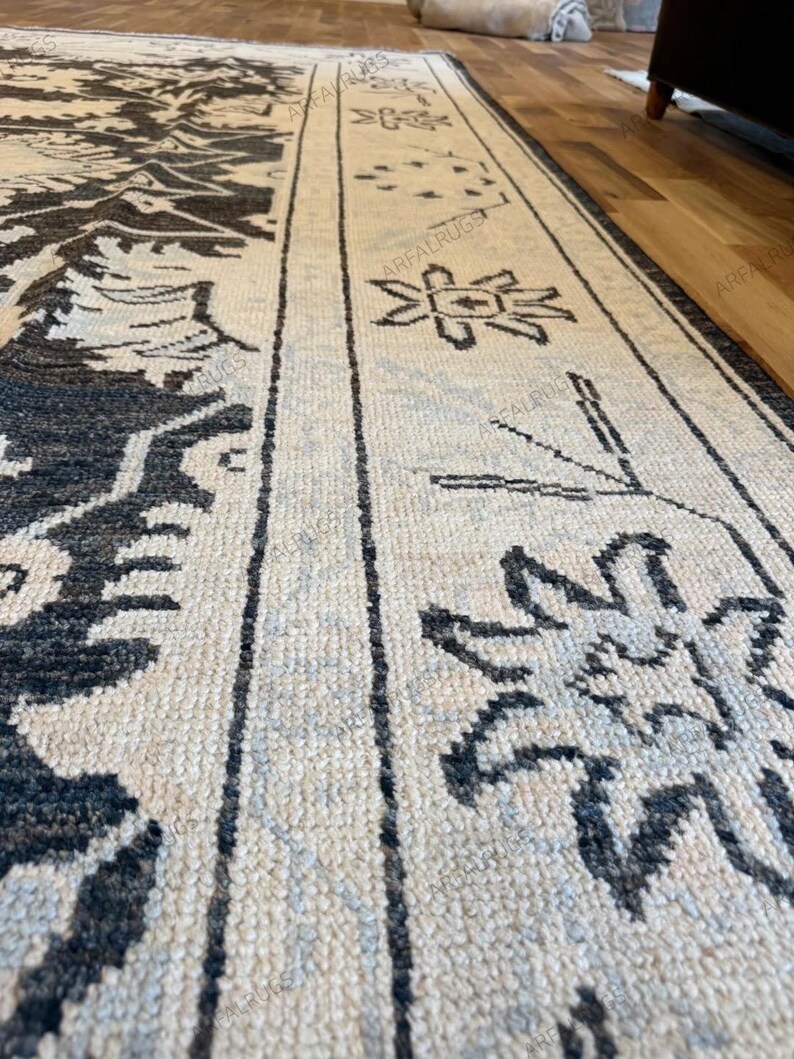 May include: A rectangular area rug featuring a cream-colored base with dark charcoal gray geometric and floral patterns. The design includes a wide border with repeating star-like motifs and linear elements, with the text ARFALRUGS visible.