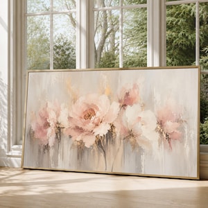Puede incluir: Una pieza de arte mural rectangular que presenta una pintura floral abstracta con pétalos de color rosa suave y crema, acentuada por sutiles detalles de pan de oro. La obra está enmarcada en un fino marco dorado metálico con estilo texturizado.