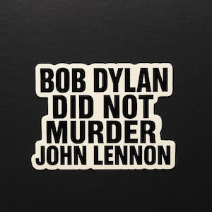 May include: A rectangular sticker with rounded corners, featuring the text "BOB DYLAN DID NOT MURDER JOHN LENNON" in bold black font on an off-white base. The sticker is set against a black background.