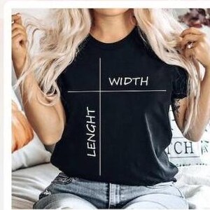 Op de afbeelding: Een zwart t-shirt met de woorden "WIDTH" en "LENGHT" in het wit, met witte lijnen die de afmetingen aangeven. Het t-shirt wordt gedragen.