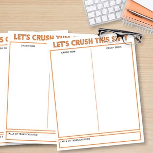 May include: Several white task planning sheets with orange borders and text that reads "LET'S CRUSH THIS SH*T". The sheets are on a wooden desk with a keyboard, glasses, and a notepad.