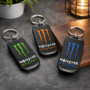 以下が含まれることがあります： エナジードリンク缶の形をした黒いキーホルダー3つ。それぞれ異なる色のロゴ（緑、オレンジ、青）が付いています。キーホルダーにはシルバーのキーリングが付いています。「MONSTER ENERGY」の文字が各キーホルダーにプリントされています。