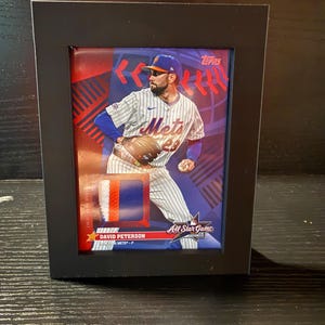 May include: A framed baseball card featuring David Peterson of the New York Mets in his uniform. The card is set against a red and blue background with the Topps logo. The frame is black.
