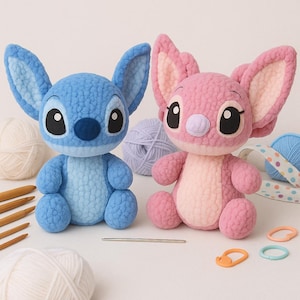 May include: Two handmade crochet plush toys, one blue and one pink, resembling cartoon characters. The blue toy has large ears and a dark blue nose. The pink toy has a light pink nose and ears. Yarn and crochet hooks are in the background.