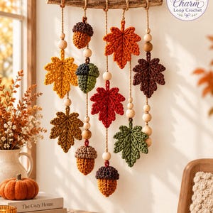 Peut inclure: Une décoration murale composée de cinq brins de feuilles et de glands crochetés suspendus à une branche de bois horizontale. Les feuilles sont dans des tons de jaune, orange, rouge, marron et vert, entremêlées de perles en bois sur de la ficelle.