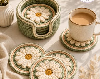 May include: A set of round crochet coasters featuring a white daisy design with a yellow center, set against a sage green and cream background. The coasters are stored in a matching sage green crochet holder, with one coaster supporting a ceramic mug.