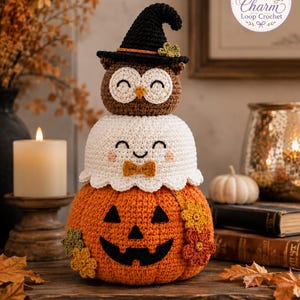 Puede incluir: Una decoración de ganchillo apilada que presenta una base de calabaza naranja con una cara de jack-o'-lantern negra, una sección central de fantasma blanco con una pequeña pajarita naranja y un búho marrón con un sombrero de bruja negro.