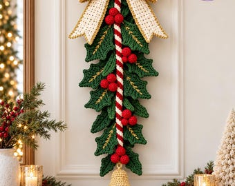 May include: A crochet Christmas wall hanging featuring a large cream-colored bow at the top, a central red and white striped candy cane pole, dark green holly leaves, clusters of red berries, and a gold-colored bell hanging at the bottom.