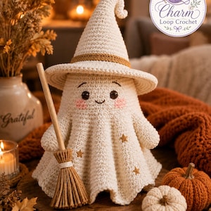 May include: A cream-colored crocheted ghost figurine wearing a pointed witch hat with a brown band. The ghost has embroidered dark eyes, a small smile, and pink cheeks, with small gold stars on its body. It holds a miniature wooden broomstick.