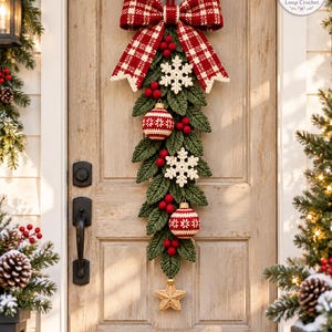 May include: A crochet Christmas door swag featuring a large red and white plaid bow at the top. The swag is composed of green crocheted leaves, red pom-poms, two white crocheted snowflakes, two red and white patterned crochet ornaments, and a gold star.