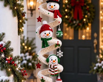 May include: A hanging spiral crochet decoration featuring three white snowmen with orange noses, wearing colorful hats and scarves. The spiral is adorned with small red stars, white snowflakes, and green and red ornaments, ending with two white pom-poms.