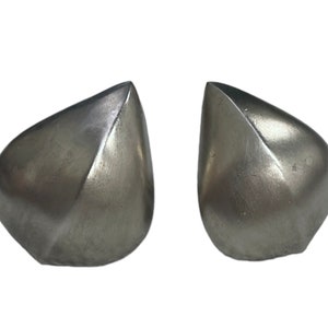 May include: Two silver-colored, teardrop-shaped bookends. Each bookend has a smooth, metallic finish with a subtle, textured appearance. The design features a geometric, faceted shape, adding a modern touch to the functional items.