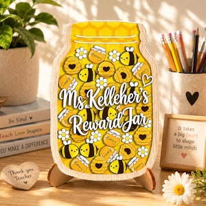 May include: A wooden jar-shaped sign featuring a yellow background with a honeycomb pattern, decorated with illustrations of bees, honey pots, and flowers. The text reads Ms. Kelleher's Reward Jar in white script lettering across the center.