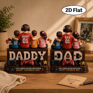 May include: Two decorative figurines for Father's Day. Each features a father figure with children, wearing headphones and holding game controllers. The base reads "DADDY" and "DAD" with the text "Happy Father's Day!"
