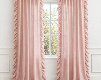 May include: A pair of floor-length, light pink curtains hanging from a black rod. Each curtain panel features a vertical ruffled edge along the side, creating a textured, layered appearance that frames the window opening.