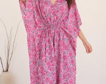 May include: A floor-length kaftan dress featuring a vibrant pink and grey floral block print pattern. The garment has a V-neckline, wide short sleeves, and a drawstring waist detail that creates a gathered effect across the midsection of the fabric.