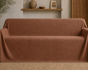 May include: A three-seater sofa covered in a solid, textured, terracotta-colored fabric throw. The fabric drapes over the back, arms, and seat of the sofa, creating a uniform, continuous appearance with a visible woven textile pattern throughout.