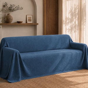 May include: A solid blue sofa cover draped over a three-seat couch. The fabric features a textured, woven appearance with a consistent deep blue colour throughout. The cover extends over the back, seat, and arms, reaching down to the floor.
