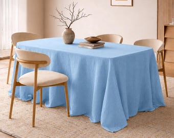 Könnte beinhalten: Ein hellblaues Leinentischtuch bedeckt einen rechteckigen Tisch, umgeben von vier beigen Stühlen. Eine Vase mit Zweigen und eine kleine Schale stehen auf dem Tisch. Der Tisch steht auf einem beigen Teppich.