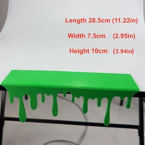 Pu&ograve; includere: Una mensola verde brillante con un design a goccia di slime. La mensola &egrave; lunga 28,5 cm, larga 7,5 cm e alta 10 cm. Le dimensioni sono indicate in centimetri e pollici.