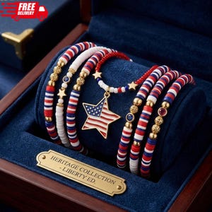 May include: A collection of patriotic bracelets and a necklace with a star pendant featuring the American flag. The bracelets are red, white, and blue, with gold accents. The set is displayed in a blue velvet-lined box with a gold plaque that reads "HERITAGE COLLECTION - LIBERTY ED."