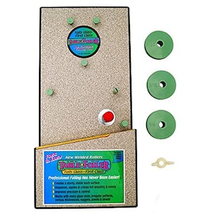 May include: A foiling tool with the text "TABLE FOILER" and "Foils Glass - First Class". The tool has a beige base with green components, a red button, and three green discs with hole sizes labeled 5.56, 4.76, and 6.35 mm.