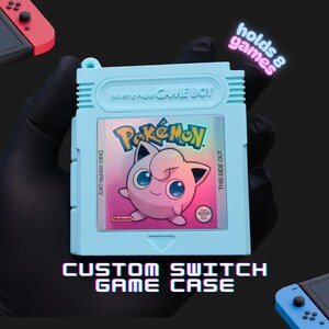 May include: A light blue Nintendo Game Boy cartridge-shaped storage case for Nintendo Switch games. The label features a pink Jigglypuff character and the text Pokémon. The case includes the text holds 8 games and custom switch game case.