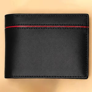 May include: Black leather wallet with a red accent stripe. The wallet is rectangular with stitched edges. The overall design is minimalist and sleek, suggesting a focus on functionality and style. The wallet appears to be new and unused.