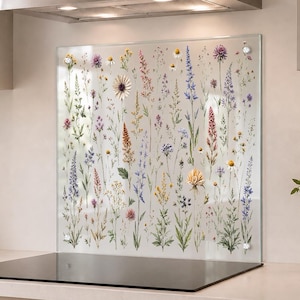 Könnte beinhalten: Eine rechteckige Küchenrückwand aus Glas mit einem botanischen Druck verschiedener Wildblumen in den Farben Violett, Blau, Gelb und Grün. Die Platte ist mit vier runden, silberfarbenen Befestigungselementen an der Wand montiert.
