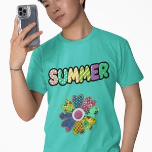 Puede incluir: Una camiseta turquesa con la palabra "SUMMER" en letras de burbujas coloridas y un diseño floral. La flor está hecha de parches de tela estampada. La persona de la imagen sostiene un teléfono.