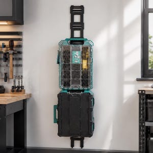Puede incluir: Un sistema modular de almacenamiento de herramientas en color verde azulado y negro montado verticalmente en una pared. La unidad superior tiene una tapa transparente con compartimentos, mientras que la inferior es una caja negra sólida sobre un riel.