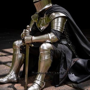 May include: A full suit of polished steel armor, including a helmet, shoulder guards, arm and leg protection, and boots. The knight is seated, holding a sword. A black cape drapes over the shoulders. The armor reflects the light, creating a metallic sheen.