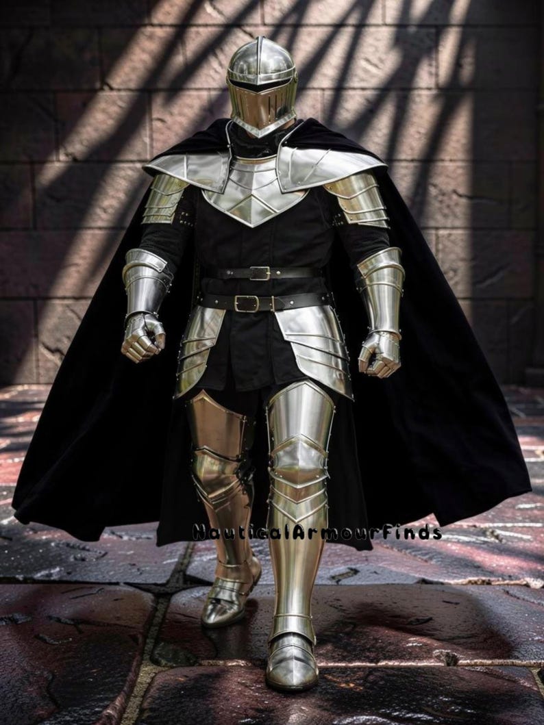 May include: A full suit of medieval armor, including a helmet, chest plate, shoulder guards, arm and leg protection, and gauntlets. The armor is silver-colored and worn over a black tunic and cape. The image is taken from a front-facing perspective.