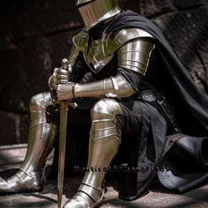 May include: A full suit of polished steel armor, including a helmet, shoulder guards, and leg protection. The knight is seated, holding a sword. A black cape drapes over the shoulders. The armor reflects the surrounding environment. The text "Nautical Armour Finds" is visible.