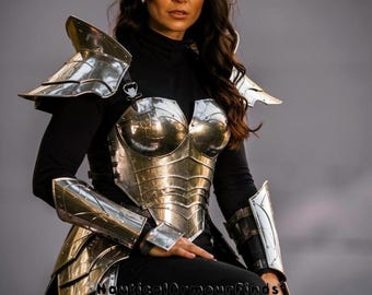 May include: A person wearing a silver metal armor set, including a breastplate, shoulder guards, arm guards, and leg guards. The armor is worn over a black top and pants. A silver metal headpiece is also worn. The armor is highly reflective.