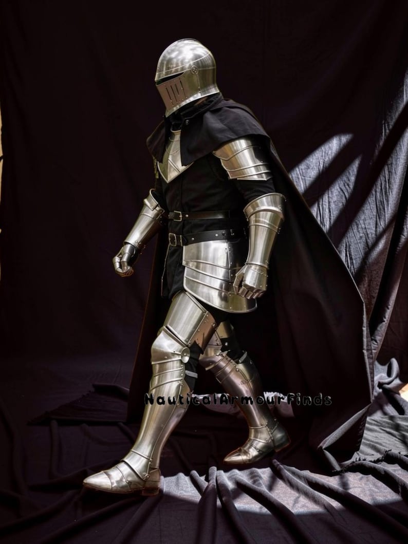 May include: A full suit of polished steel armor, including a helmet, chest plate, arm and leg guards, and gauntlets. The armor is worn over a black tunic and cape. The image shows the armor from the side, with the person walking forward. The text "Nautical Armour Finds" is visible.