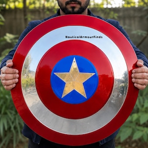 May include: A circular shield featuring a metallic red outer ring, a silver middle ring, and a blue center circle with a gold five-pointed star. The text NauticalArmourFinds is printed in black on the silver ring. The shield has a polished finish.