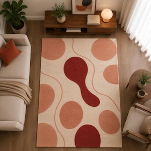 May include: A rectangular area rug with a cream background and a pattern of large, overlapping circles in shades of red and peach. Wavy lines connect the circles, creating a modern, abstract design. The rug is placed in a living room setting.