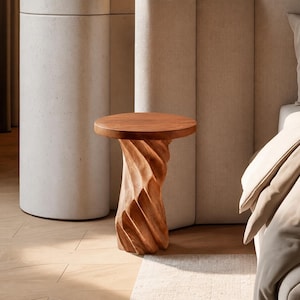 May include: A small side table crafted from light brown wood, featuring a smooth, circular tabletop and a base with a distinct, vertical, spiralling, or twisted carved texture that extends from the top down to the floor.