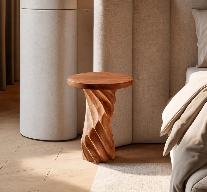 May include: A small side table crafted from light brown wood, featuring a smooth, circular tabletop and a base with a distinct, vertical, spiralling, or twisted carved texture that extends from the top down to the floor.