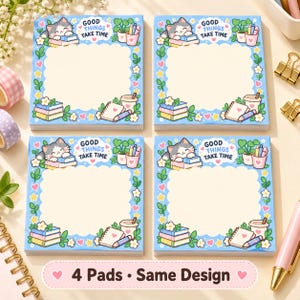May include: Four square sticky note pads featuring a light blue border with a scalloped cream center. The design includes a cartoon cat, stacked books, a potted plant, a coffee cup, and the text "GOOD THINGS TAKE TIME" in blue lettering.