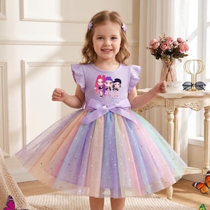 Peut inclure: Une robe lilas avec une jupe en tulle arc-en-ciel. La robe présente un nœud à la taille et un graphisme de trois personnages de dessins animés sur le corsage. La robe a des manches à volants et convient à une jeune fille.