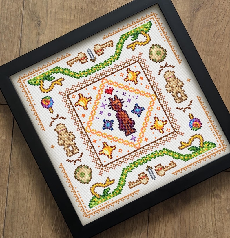 Puede incluir: Obra de arte de punto de cruz enmarcada, con un dise&ntilde;o central de gato con estrellas y corazones. La obra incluye llaves, momias y un borde verde en forma de serpiente. Ideal para la decoraci&oacute;n del hogar.