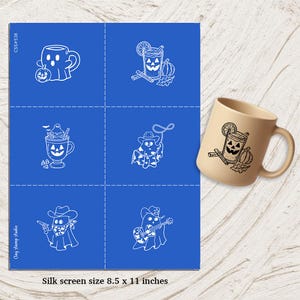 May include: A tan ceramic mug with a black Halloween-themed design featuring a cocktail, pumpkin, and cinnamon sticks. The image also shows a blue sheet with white illustrations of Halloween-themed designs, including a ghost cowboy and a ghost playing guitar. The sheet is 8.5 x 11 inches.