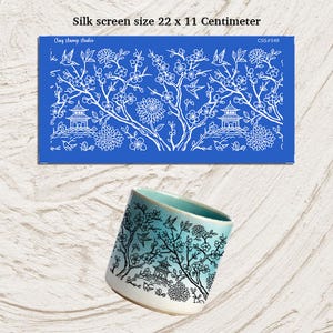May include: A blue silk screen stencil with a white floral and pagoda design, measuring 22 x 11 centimeters. A ceramic cup with a similar design is also shown, featuring a gradient of blue and white.