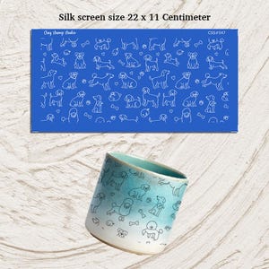 May include: A blue silk screen with white dog illustrations, measuring 22 x 11 centimeters, is displayed above a ceramic mug with a dog pattern. The mug has a blue and white gradient and features various dog breeds.